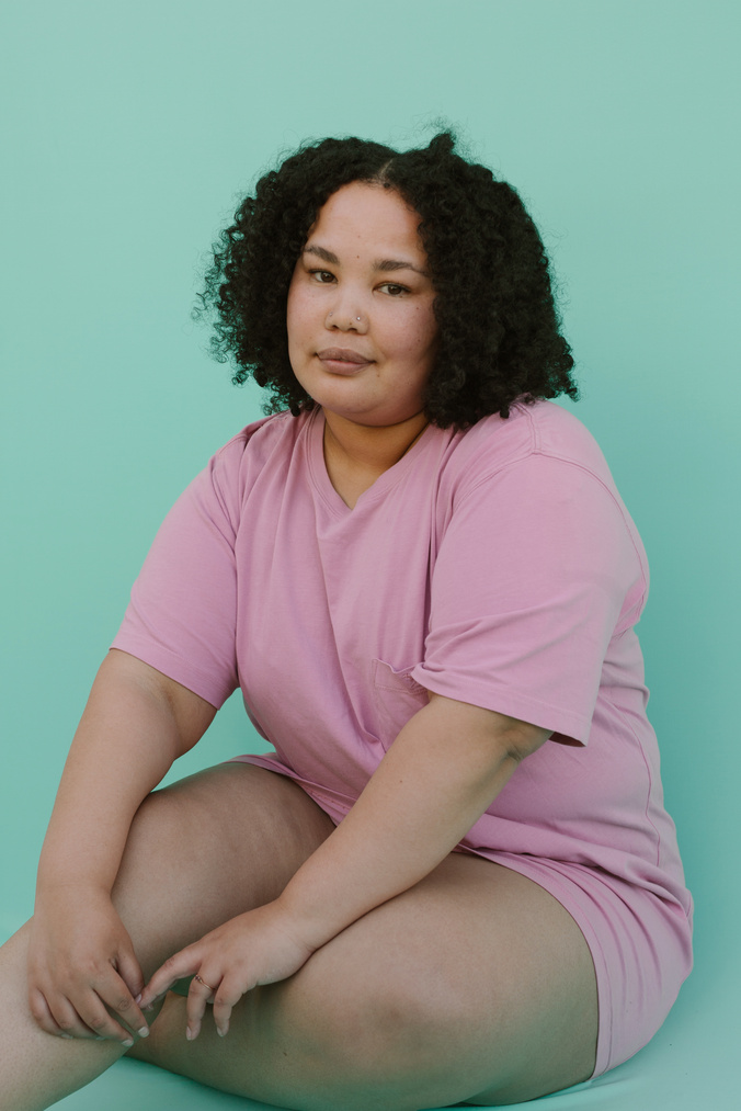 Woman in Pink Shirt Sitting against Green Background